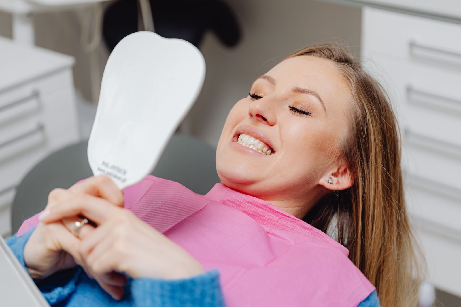 Happy Ceres Dental patient smiling and checking her results in a mirror